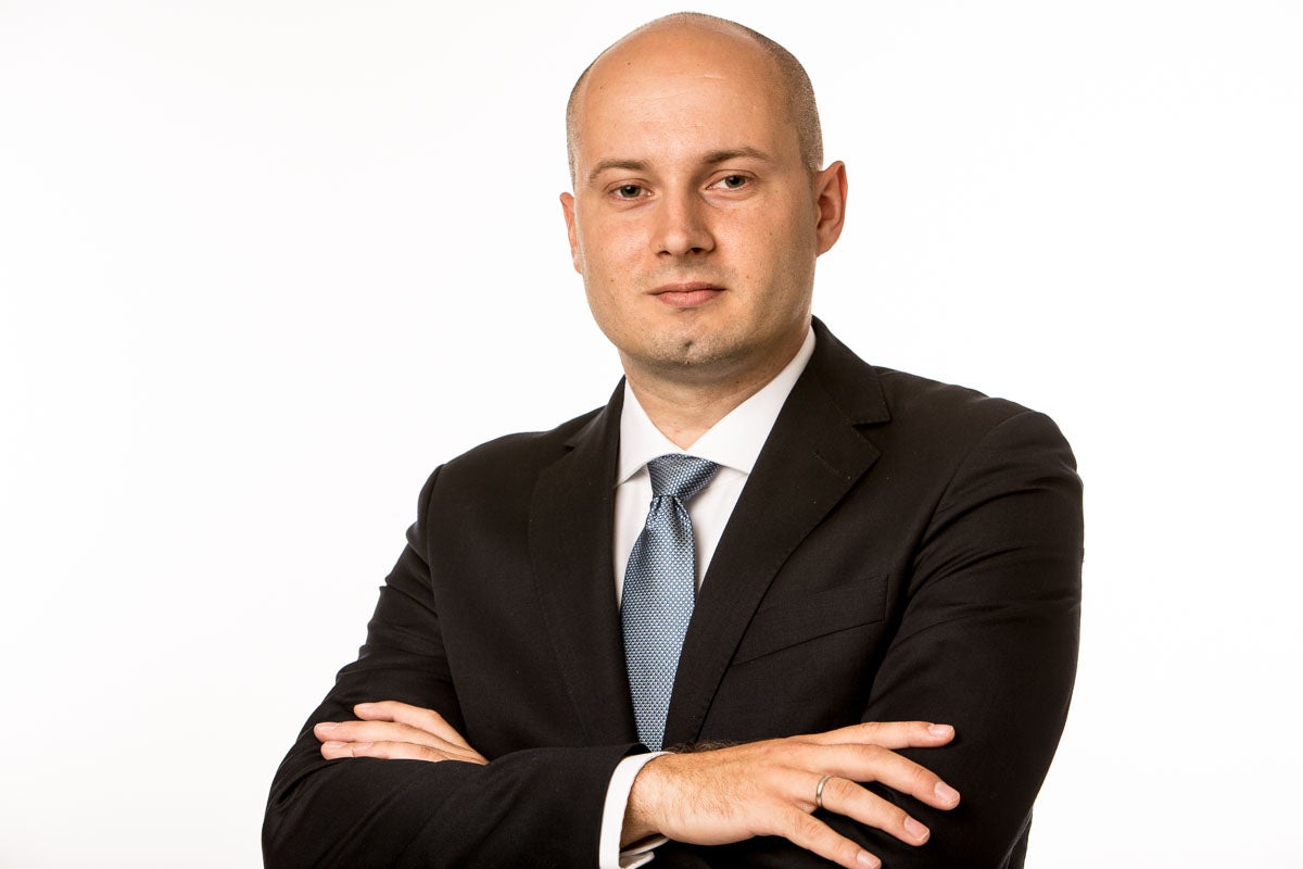 Man wearing a suit with arms crossed smiling