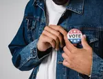 Man pinning Vote button to jacket